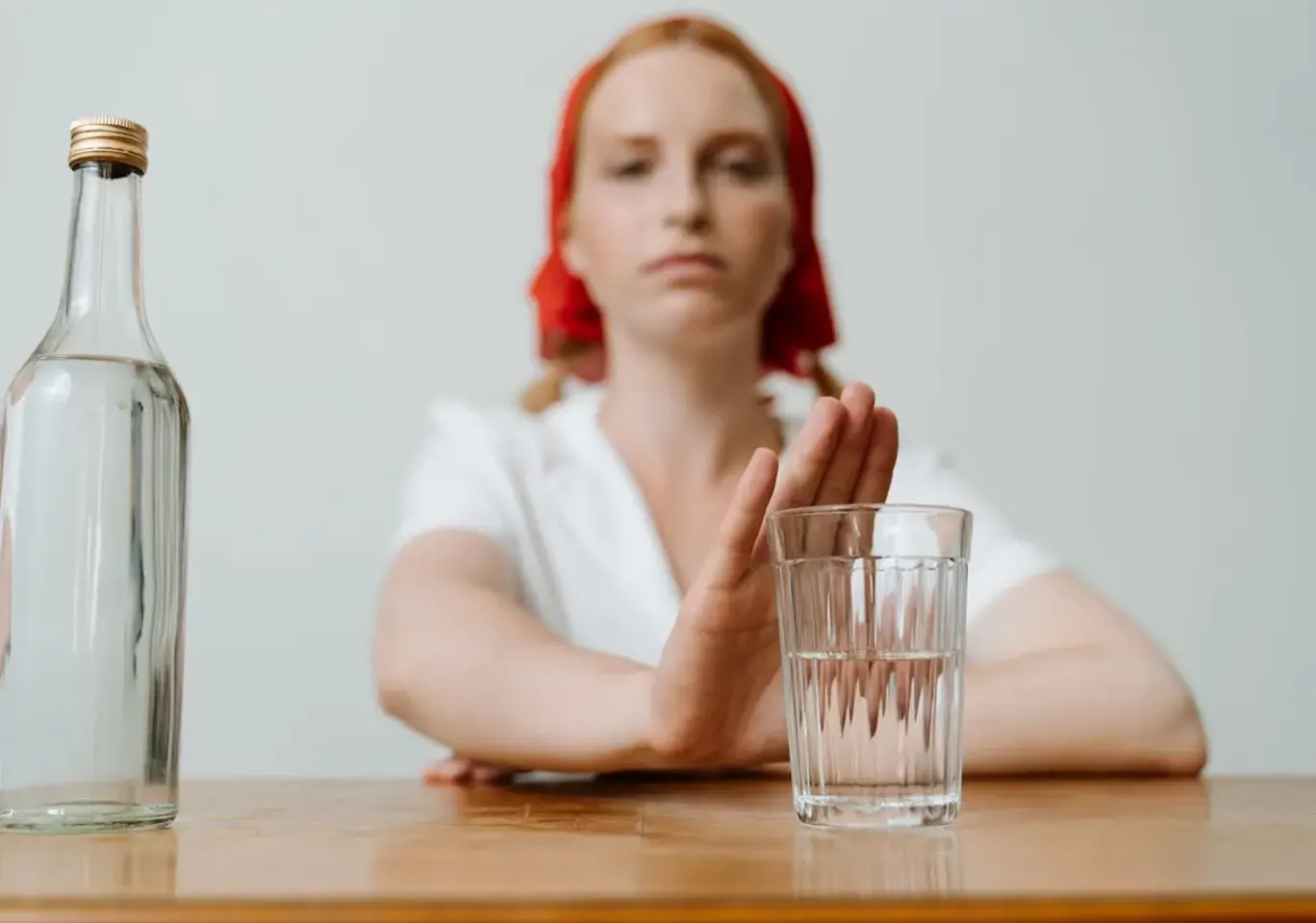 Leczenie alkoholizmu Łódź: kobieta odsuwa butelkę i sięga po wodę