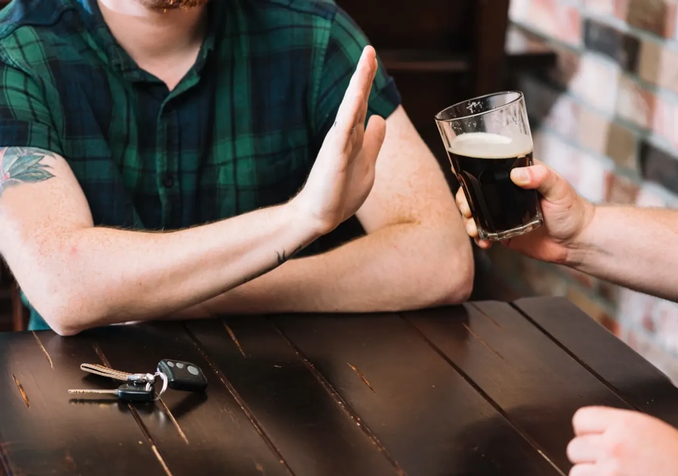 Leczenie alkoholizmu Łódź: dłoń odmawiająca kufla piwa przy stole